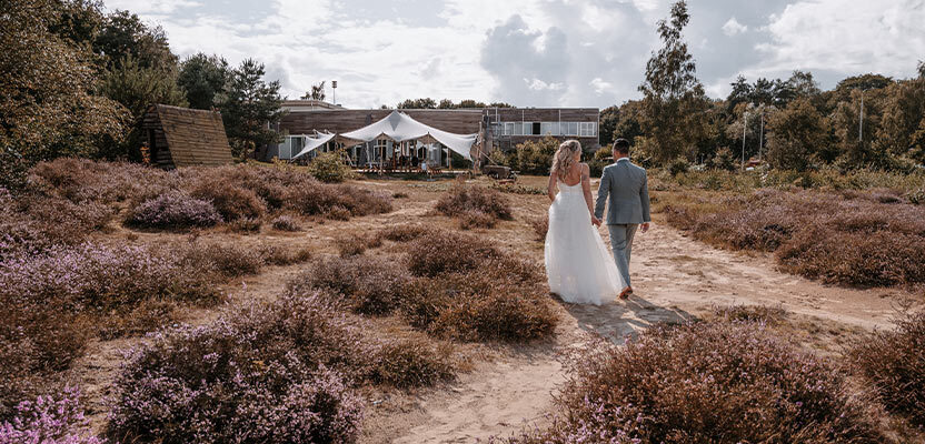 Stel loopt over de heide na hun bruiloft in de natuur