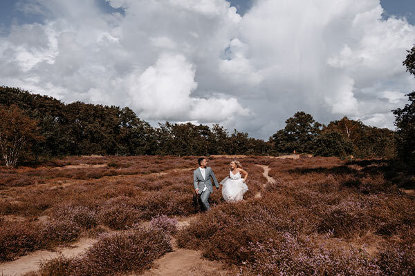 Bruidspaar rent over de heide bij De Zeegser Duinen