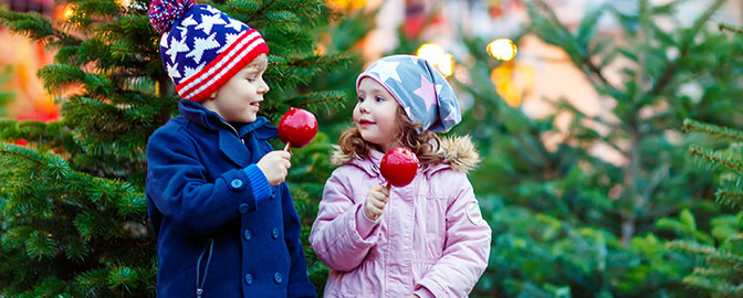 Kinderen op de kerstmarkt met een snoep appel