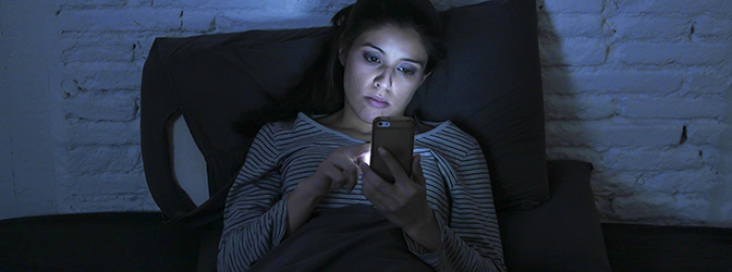 Vrouw kijkt op haar mobiel in bed