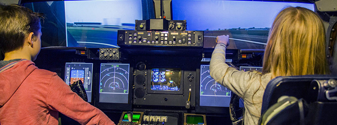 Kinderen in de vliegtuigsimulator van Aviodrome