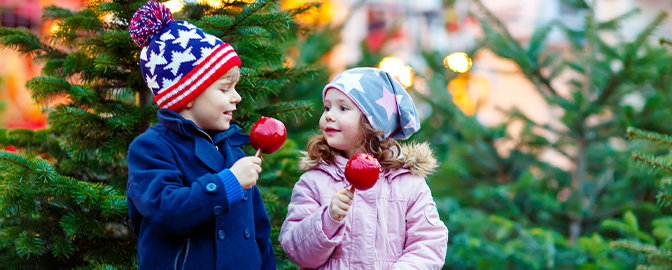 Kinderen op de kerstmarkt met een snoep appel